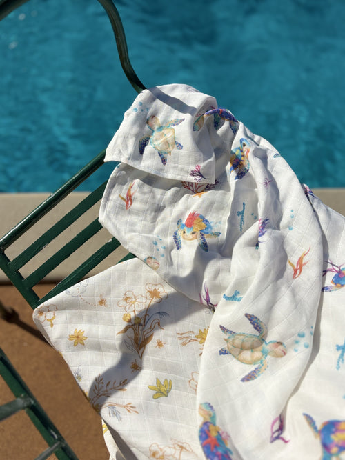 Any 2 Muslin Blankets Bundle - two Ari Baby muslin swaddle prints draped over a poolside chair
